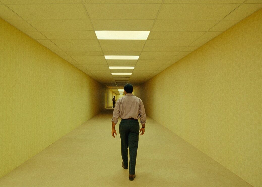 Un hombre avanza por un pasillo amarillo e interminable en Backrooms